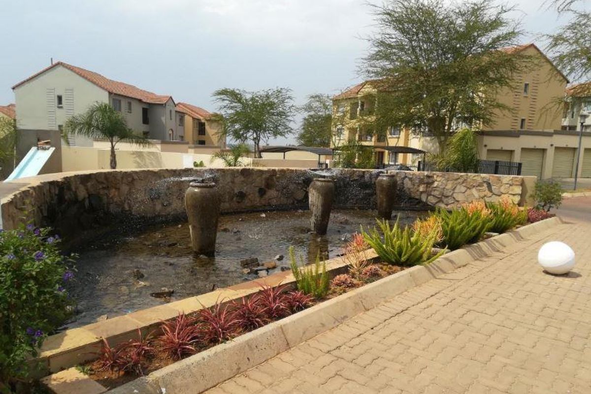 A landscaped communal water feature with stone cladding and decorative urns located within the apartment complex grounds.