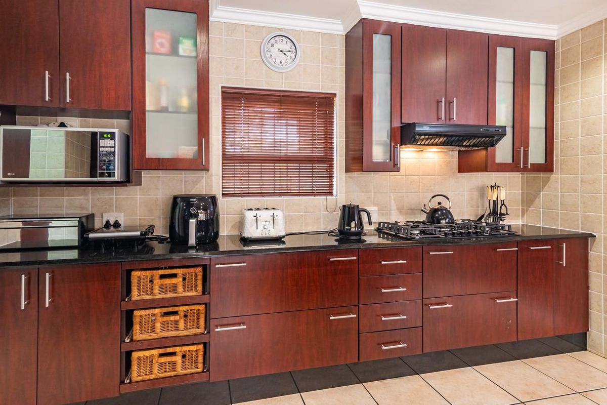 A well-maintained kitchen featuring dark wood cabinetry, granite countertops, a gas hob with extractor fan, and a built-in microwave.