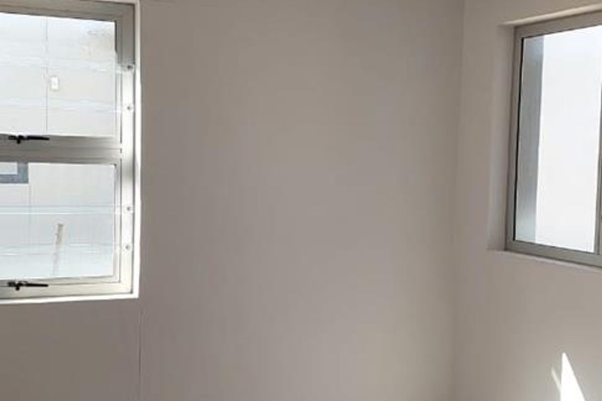 A bright, empty bedroom featuring neutral tiled flooring, clean walls, and aluminium-framed windows, offering a versatile space ready for personalization.