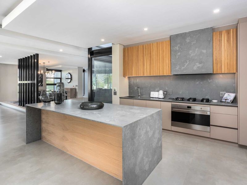 Modern open-plan kitchen featuring a large stone-topped island, integrated cabinetry, high-end built-in appliances, and sleek contemporary finishes throughout.
