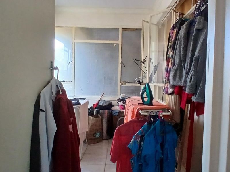 A functional laundry or utility space featuring tiled flooring and large windows, offering potential for modernization and improved storage organization.