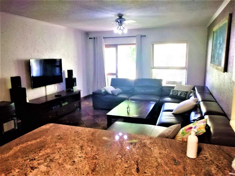 Open plan living area featuring a granite breakfast bar, tiled flooring, and direct access to the outdoor space through a sliding glass door.