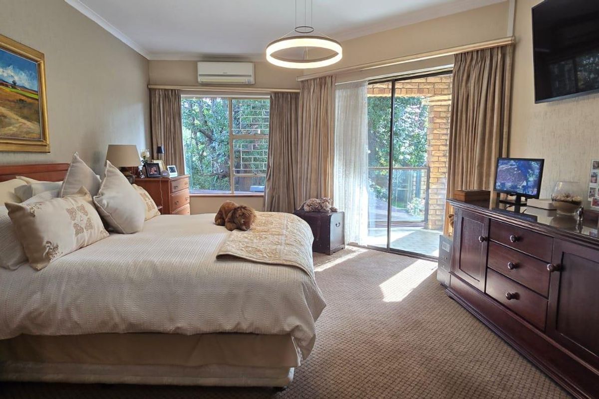 Spacious bedroom featuring carpeted flooring, a wall-mounted air conditioning unit, and sliding glass doors providing access to an outdoor patio area.