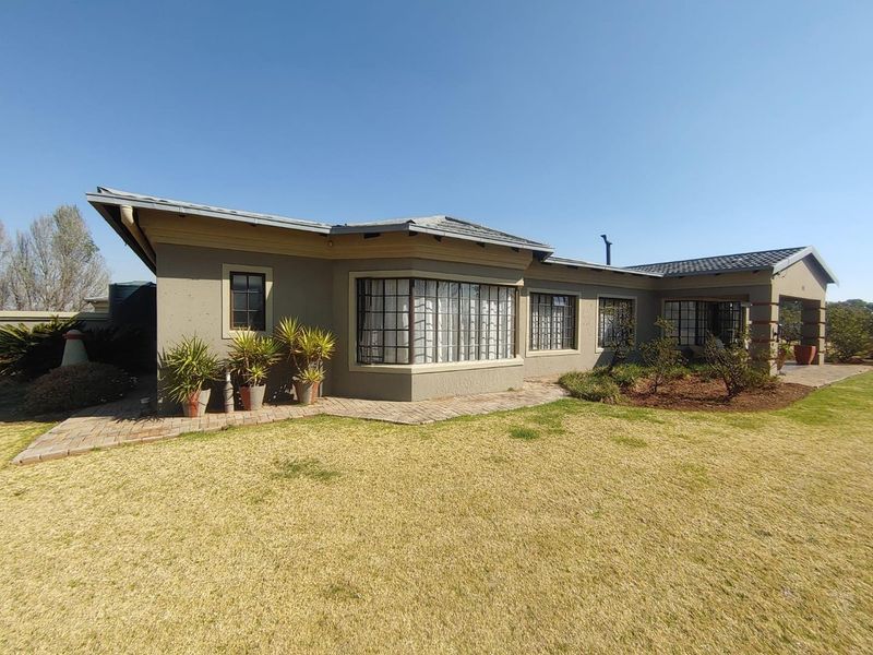 Rear view of the property featuring a bay window, paved walkway, and established garden area with a tiled roof structure.