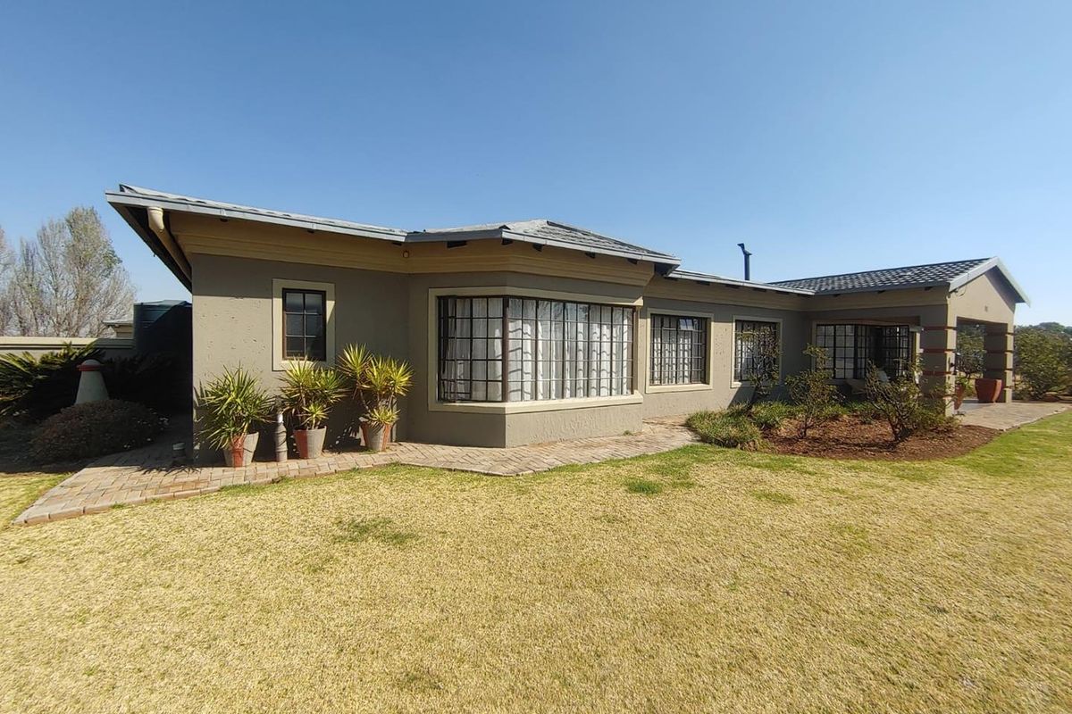 Rear view of the property featuring a bay window, paved walkway, and established garden area with a tiled roof structure.