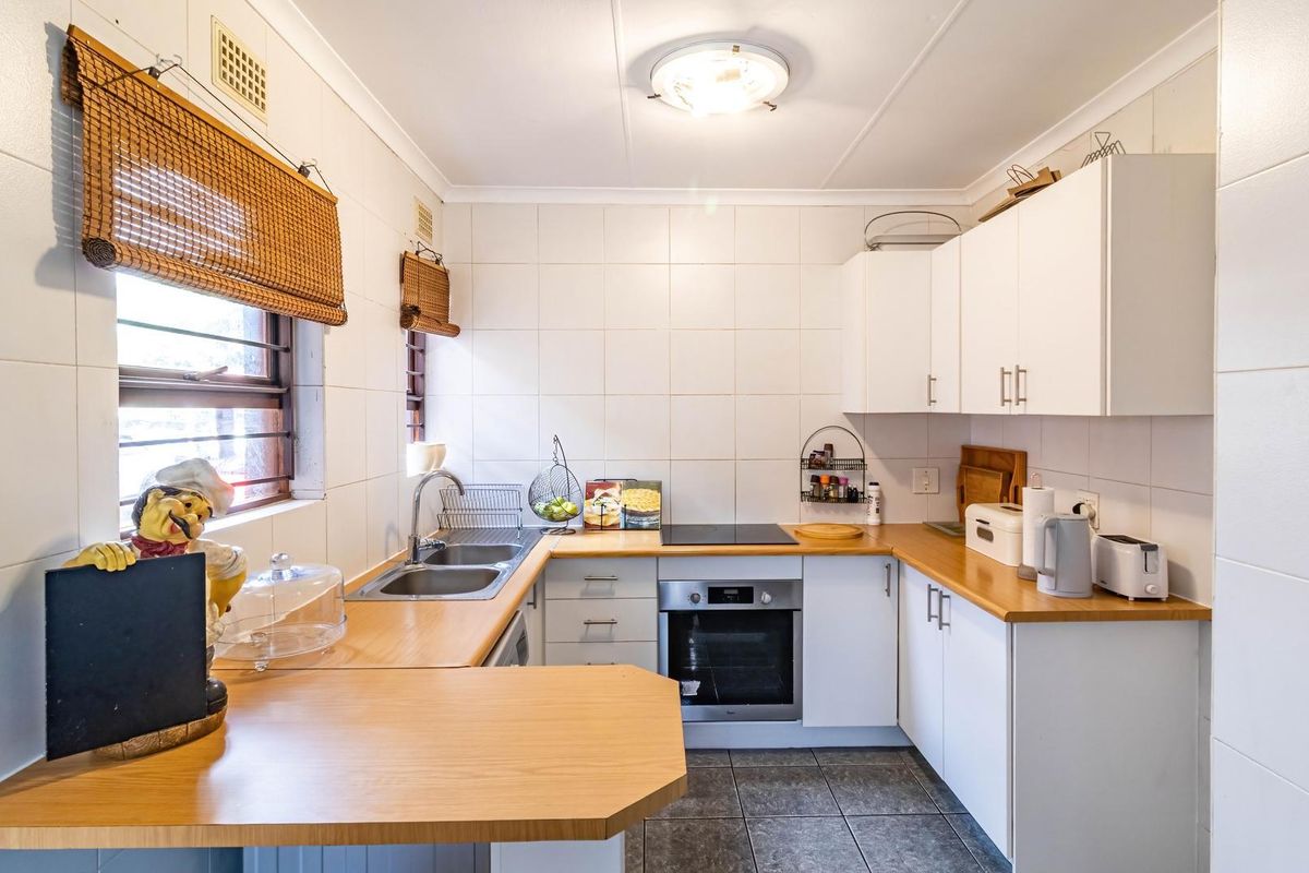 A functional kitchen featuring white cabinetry, laminate countertops, a built-in oven, electric cooktop, and tiled splashbacks.