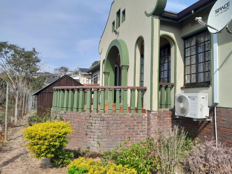 Front elevation of a character home featuring an arched entrance, brick base, and a decorative balustrade porch area.