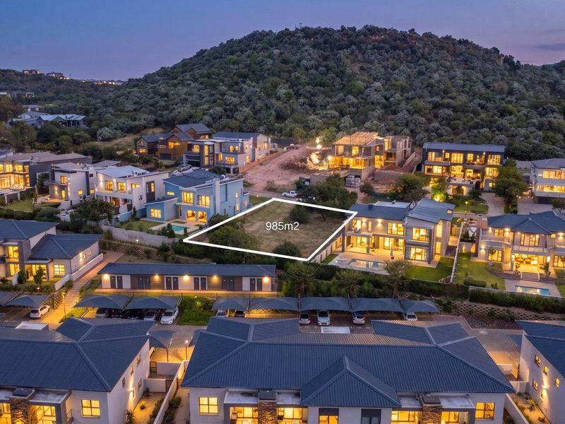 An aerial view of a 985m2 vacant residential plot situated within a developed estate, surrounded by modern homes.