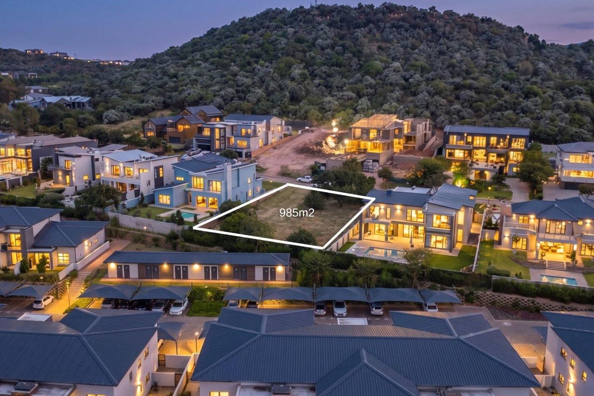 An aerial view of a 985m2 vacant residential plot situated within a developed estate, surrounded by modern homes.