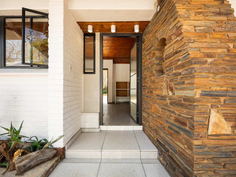 Inviting entrance featuring a combination of natural stone cladding, painted brickwork, and a warm timber ceiling with modern recessed lighting.