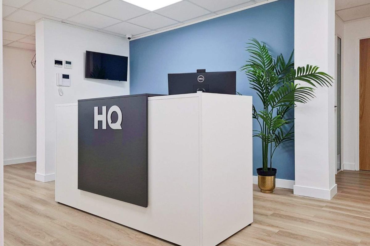 Modern office reception area featuring a clean reception desk, wood-look laminate flooring, and a professional blue accent wall.