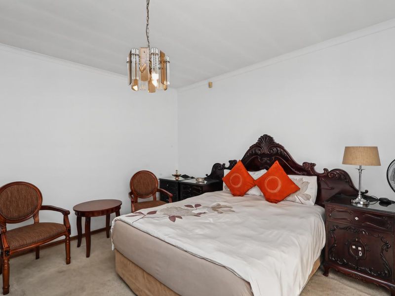 A well-proportioned bedroom featuring neutral wall finishes, carpeted flooring, and a central ceiling light fixture.