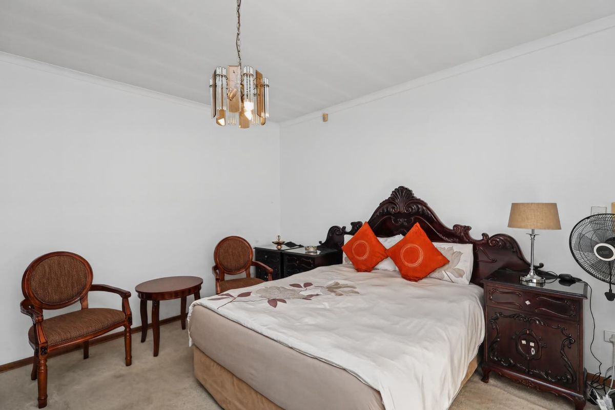 A well-proportioned bedroom featuring neutral wall finishes, carpeted flooring, and a central ceiling light fixture.