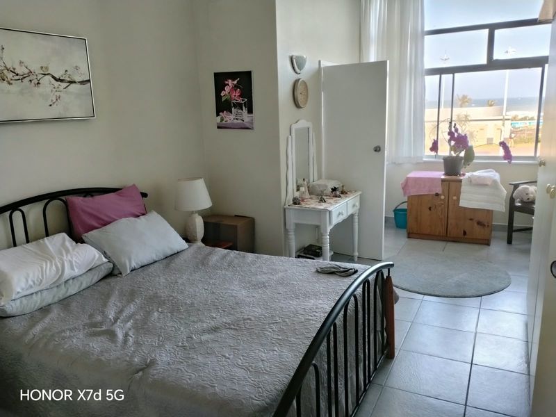 A bedroom featuring tiled flooring and a large window with natural light, offering a view of the exterior.
