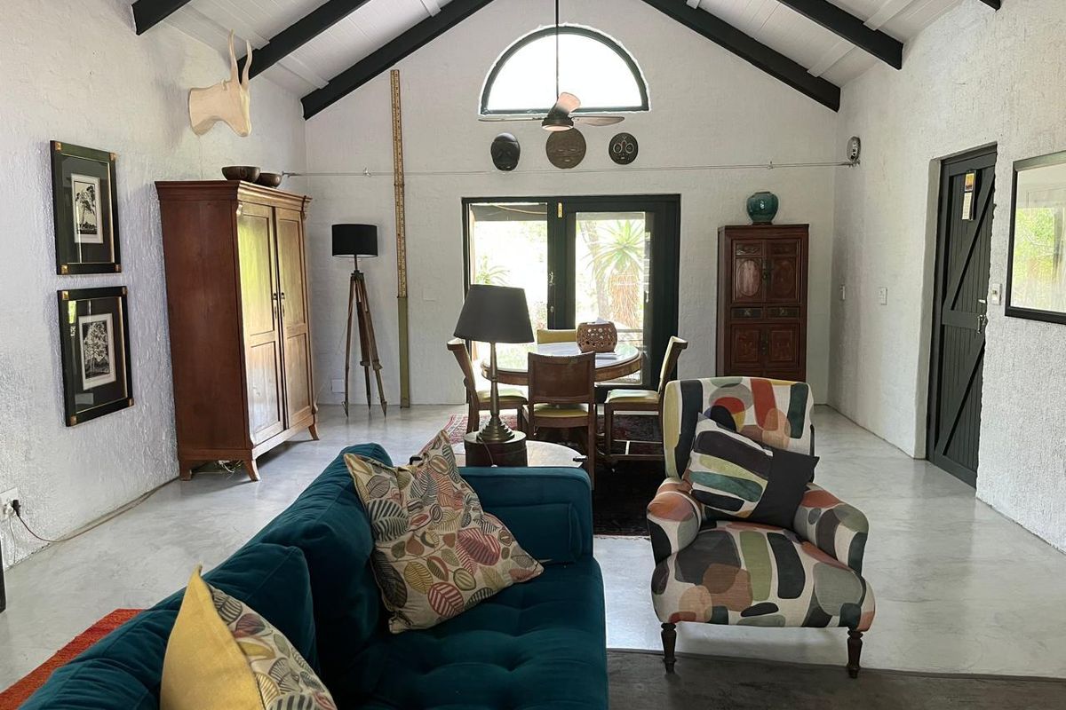 Spacious living room featuring a high vaulted ceiling with exposed beams, polished concrete floors, and an arched window providing natural light.
