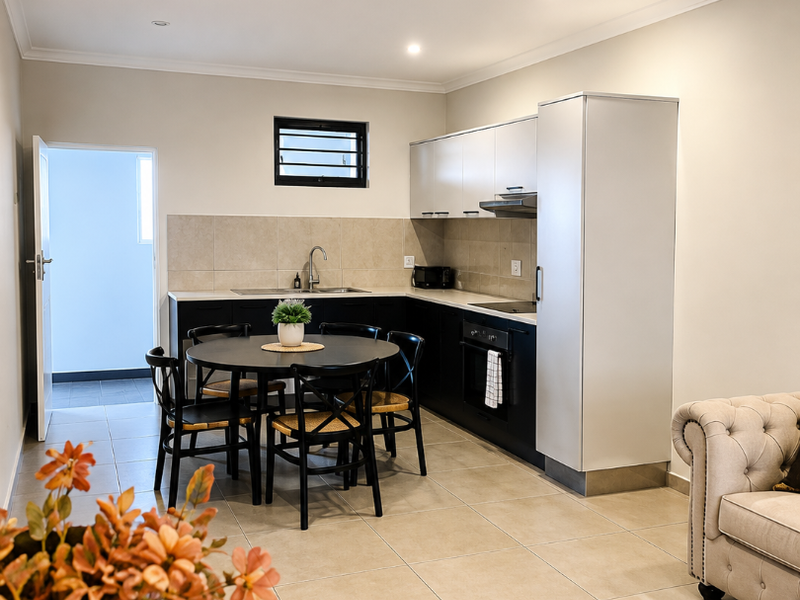 Modern open-plan kitchen featuring sleek cabinetry, integrated appliances, and neutral tiled flooring, seamlessly flowing into the living area.