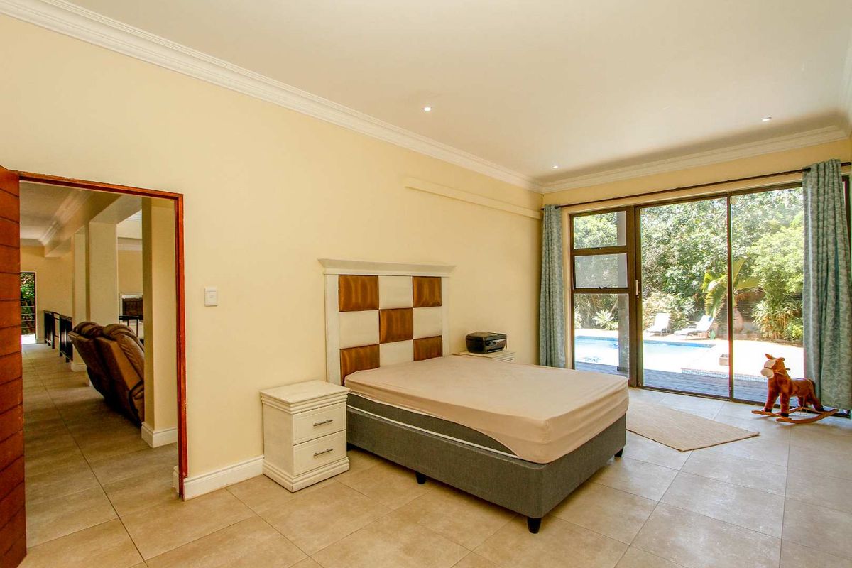 Spacious bedroom featuring tiled flooring, crown molding, and large sliding glass doors providing direct access to the outdoor pool area.
