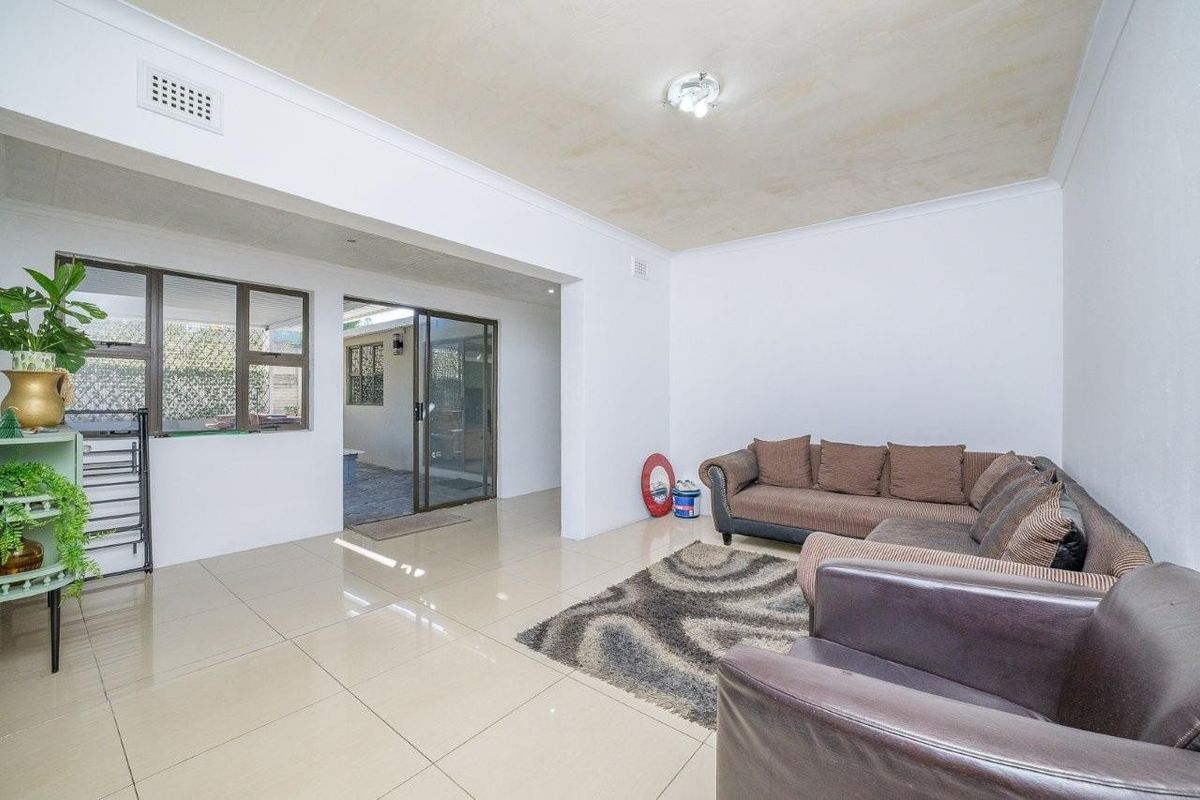 Spacious living area featuring large format floor tiles, neutral walls, and sliding glass doors providing access to the outdoor patio area.