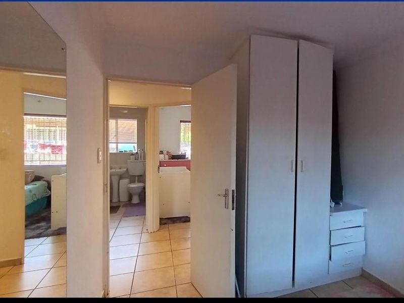 A functional hallway area featuring tiled flooring and a built-in wardrobe, providing access to adjacent bedroom and bathroom spaces.