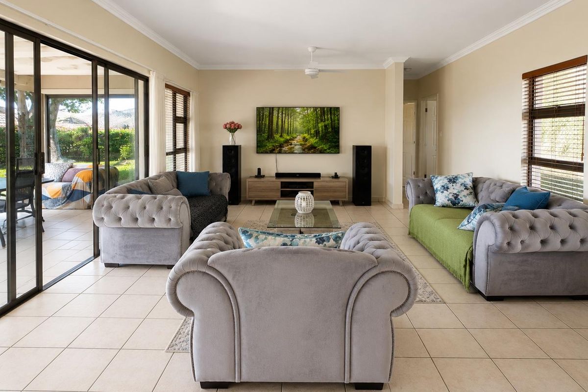 Spacious living room featuring large sliding glass doors leading to a patio, tiled flooring, and a ceiling fan.
