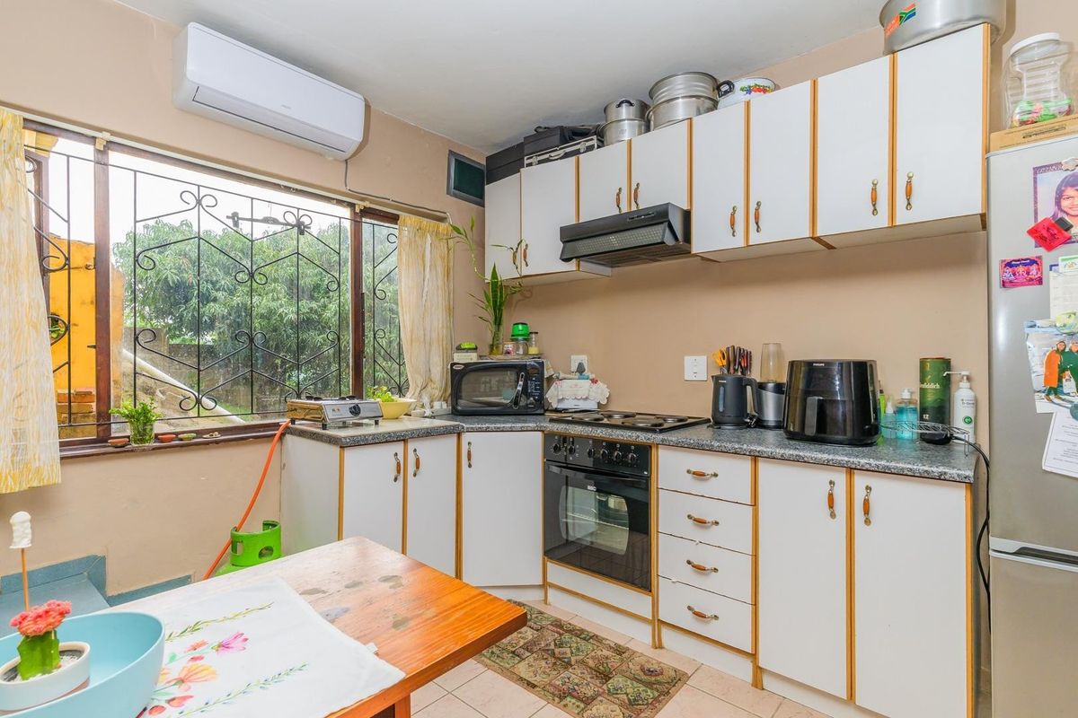 Functional kitchen featuring built-in cabinetry, laminate countertops, integrated oven, hob, extractor fan, and a split-system air conditioner for climate control.