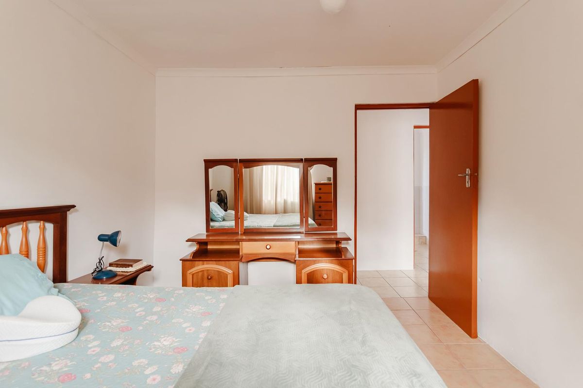 A functional bedroom featuring tiled flooring and a solid core door, providing access to an adjacent room.