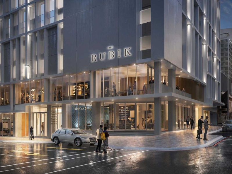 Modern multi-story commercial office building featuring a prominent glass facade, ground-level retail space, and contemporary architectural design in an urban setting.