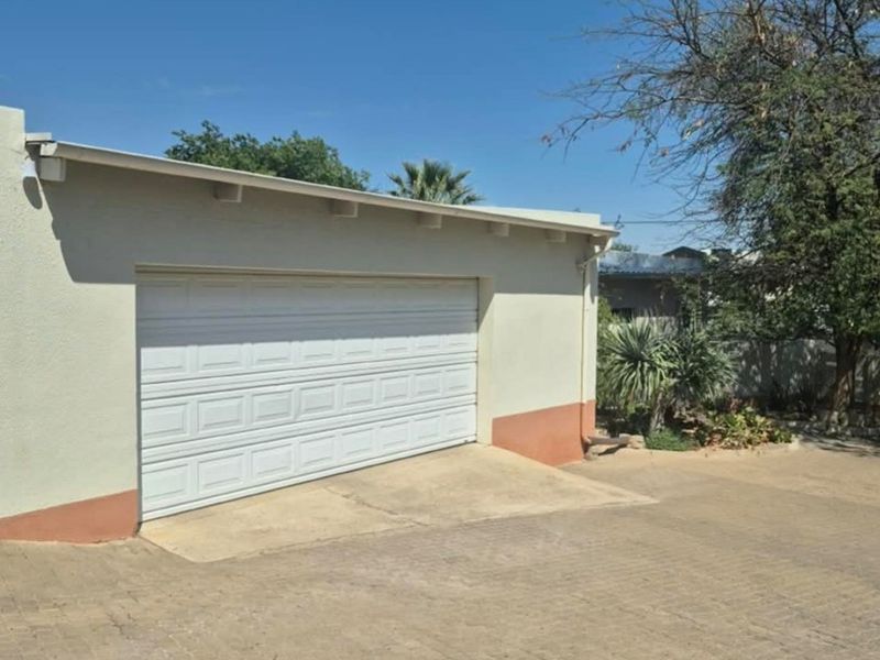 Exterior view of a single garage featuring a white sectional door and a paved driveway area.