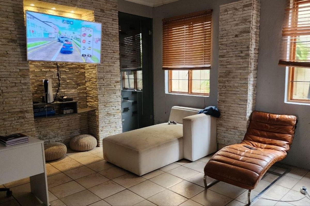 A living room featuring a stone-clad feature wall, tiled flooring, and wooden venetian blinds.