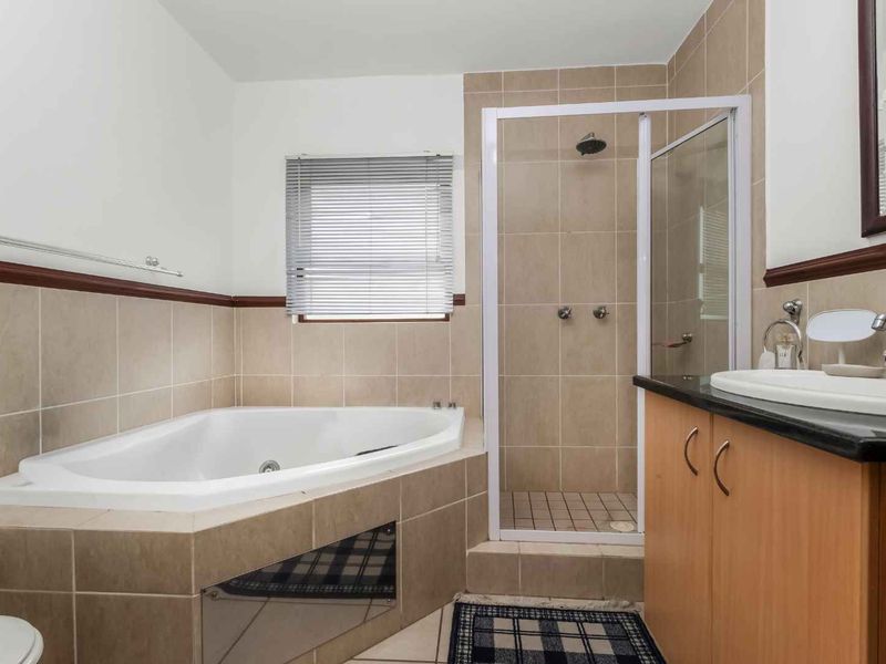 A functional bathroom featuring a corner bathtub, separate shower enclosure, and a vanity cabinet with a basin.