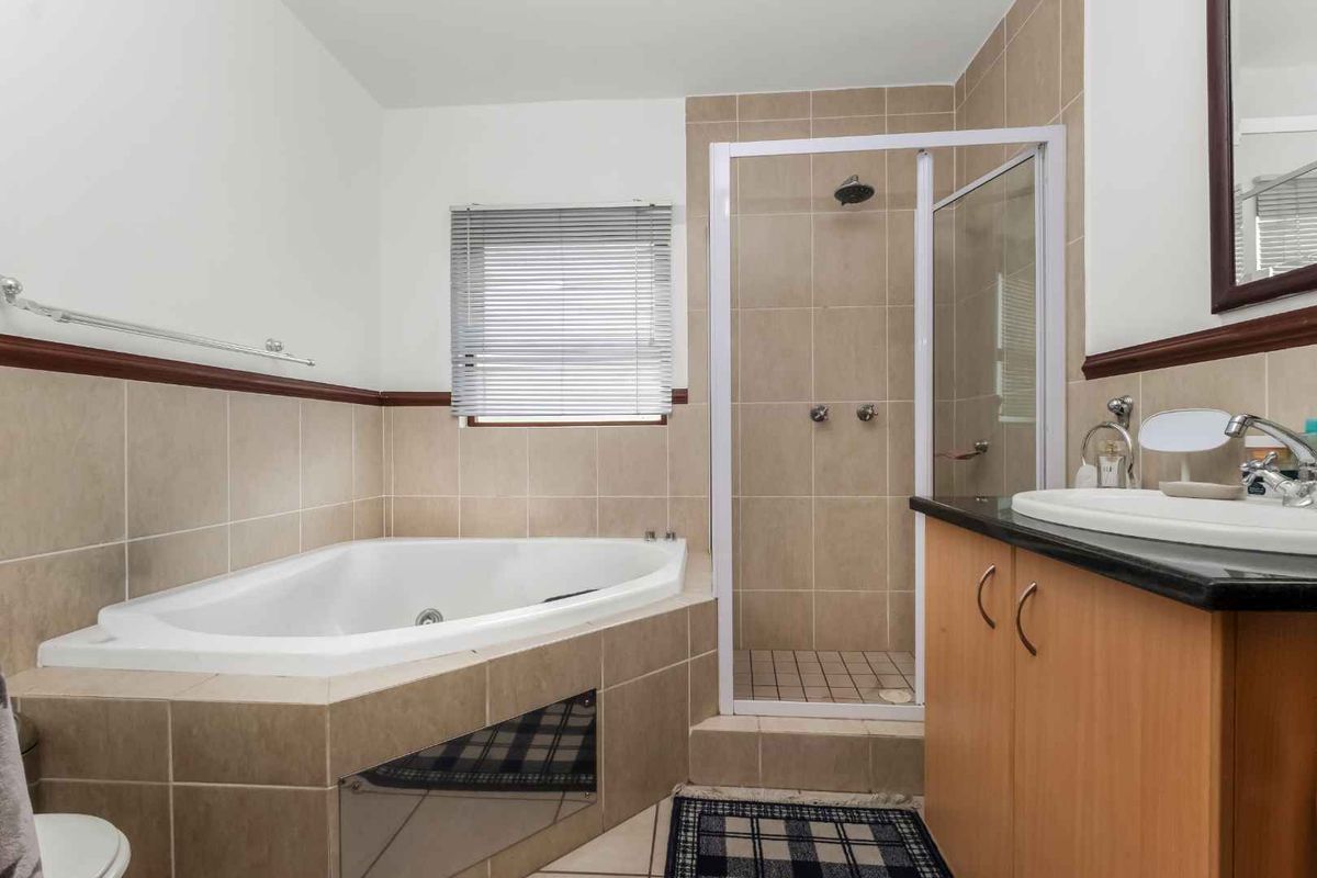A functional bathroom featuring a corner bathtub, separate shower enclosure, and a vanity cabinet with a basin.