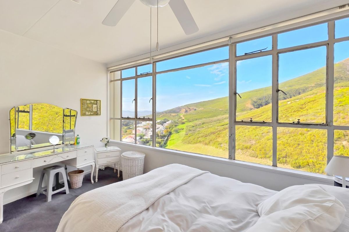 Bright bedroom featuring expansive windows with scenic mountain views and a ceiling fan.