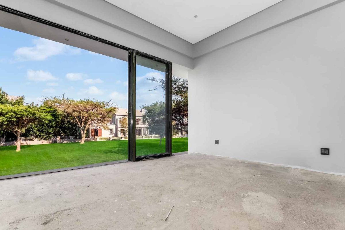 An unfinished interior living space featuring large sliding glass doors that open onto a landscaped garden area.