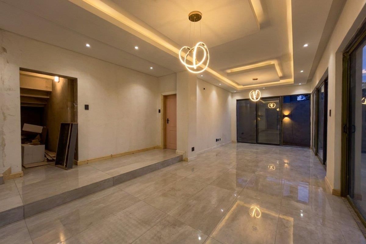 Spacious, modern living area featuring large format floor tiles, recessed bulkhead lighting, and sliding glass doors leading to the exterior.
