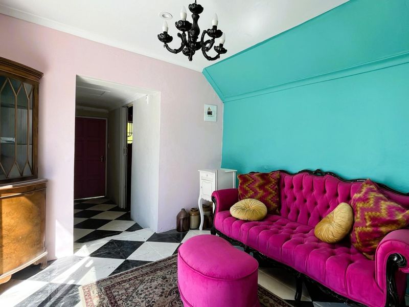 A living room area featuring a distinctive checkered floor and a chandelier, showcasing a bold and eclectic interior design style.