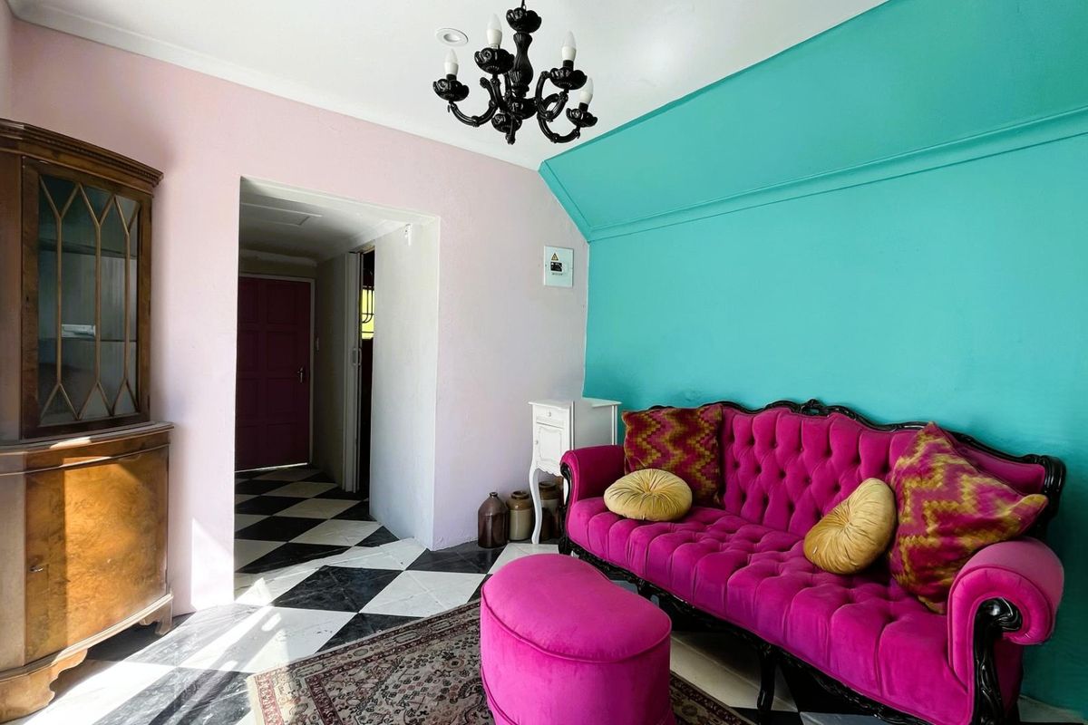 A living room area featuring a distinctive checkered floor and a chandelier, showcasing a bold and eclectic interior design style.