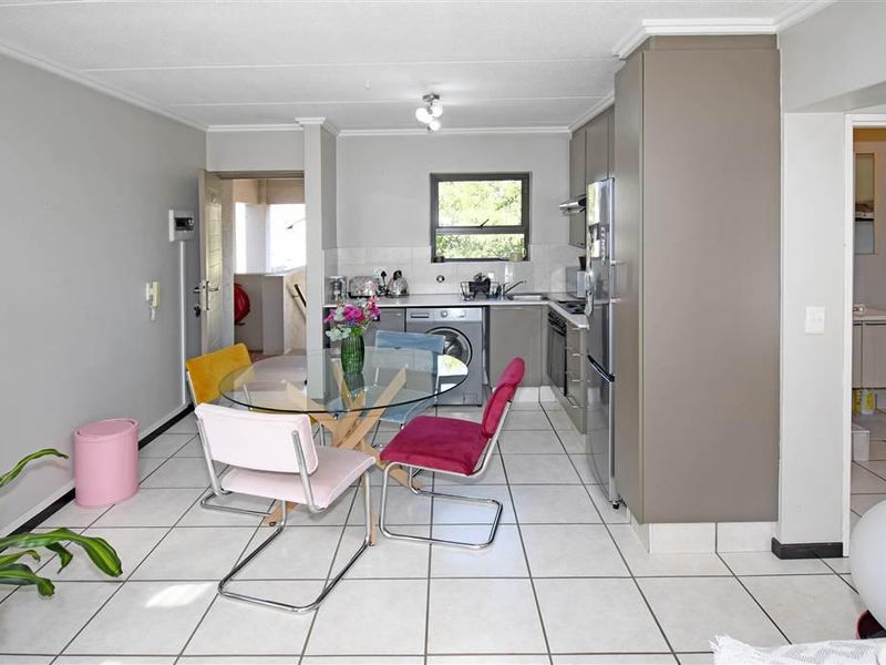 Open-plan kitchen and dining area featuring tiled flooring, built-in cabinetry, and integrated appliances, providing a functional and connected living space.