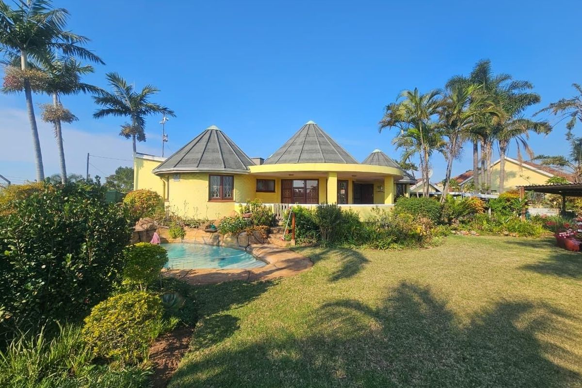 Rear view of a unique yellow house featuring conical roofs, a swimming pool, and a well-maintained garden area.