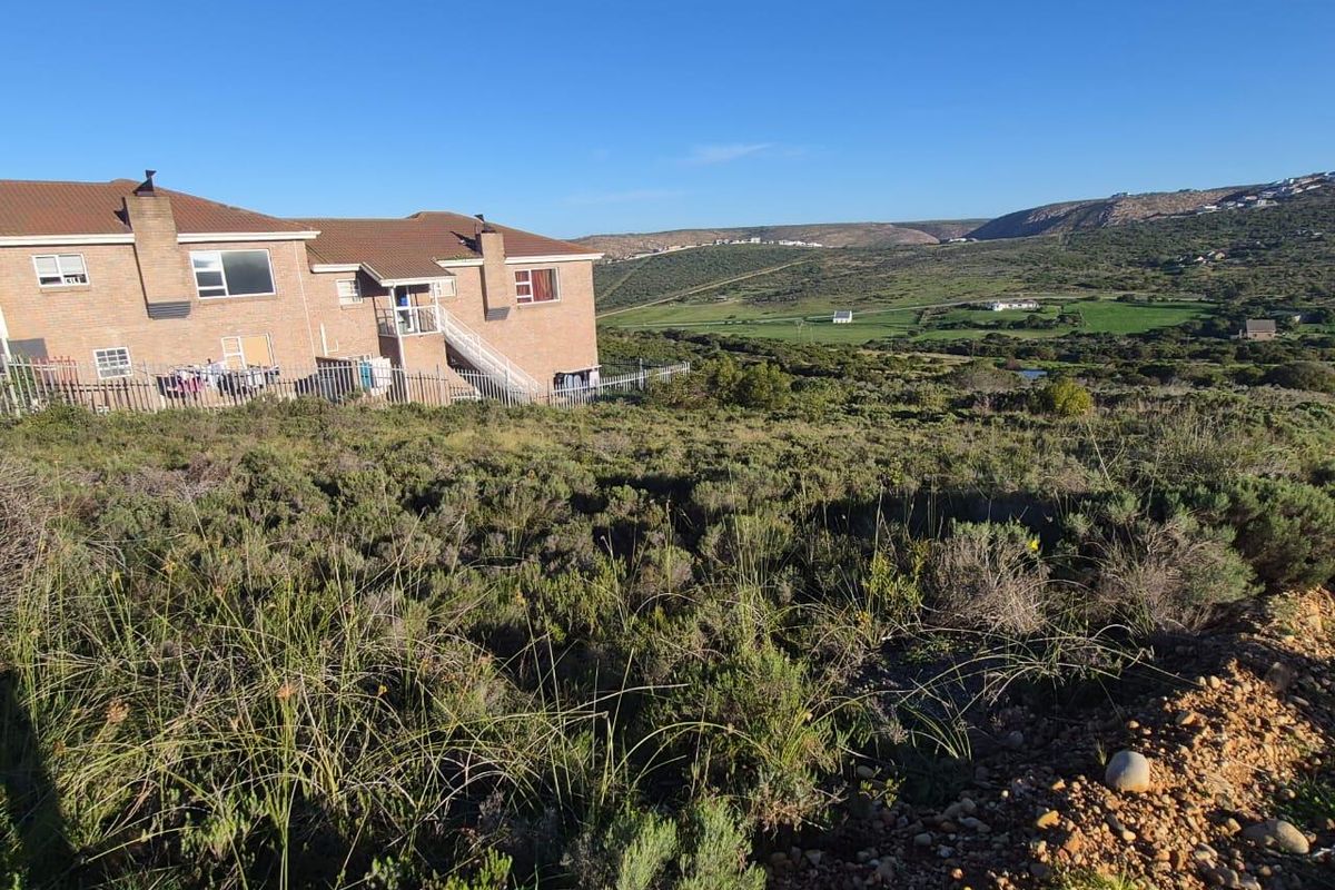 A view of the vacant residential land featuring natural vegetation with adjacent residential buildings and a scenic landscape backdrop.