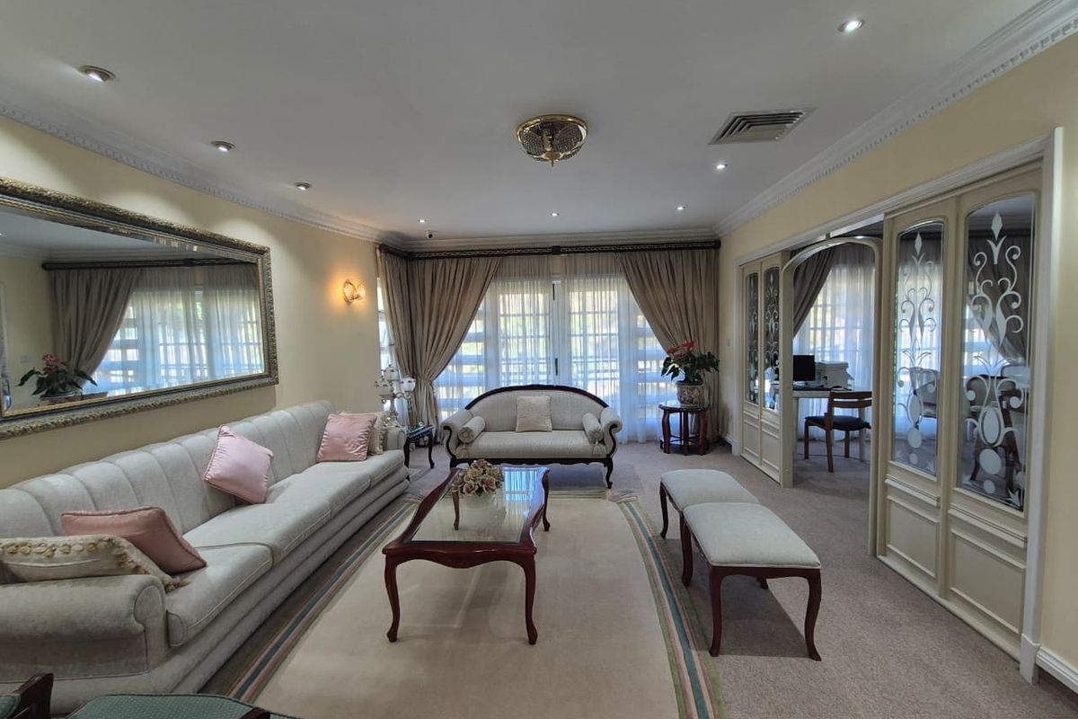 Spacious living room featuring decorative coving, recessed lighting, and elegant glass-panelled room dividers leading to an adjacent study area.