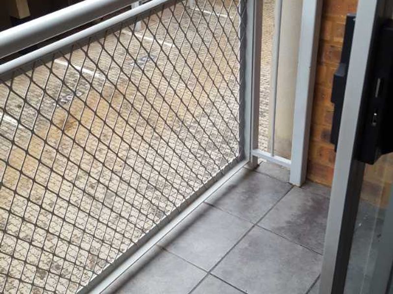A compact balcony featuring tiled flooring and a secure metal balustrade, offering an outdoor space accessible via a sliding glass door.