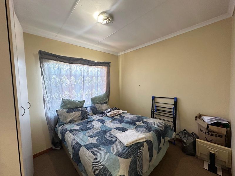 A standard bedroom featuring carpeted flooring, a built-in wardrobe, and a ceiling light fixture, providing a functional space for rest.