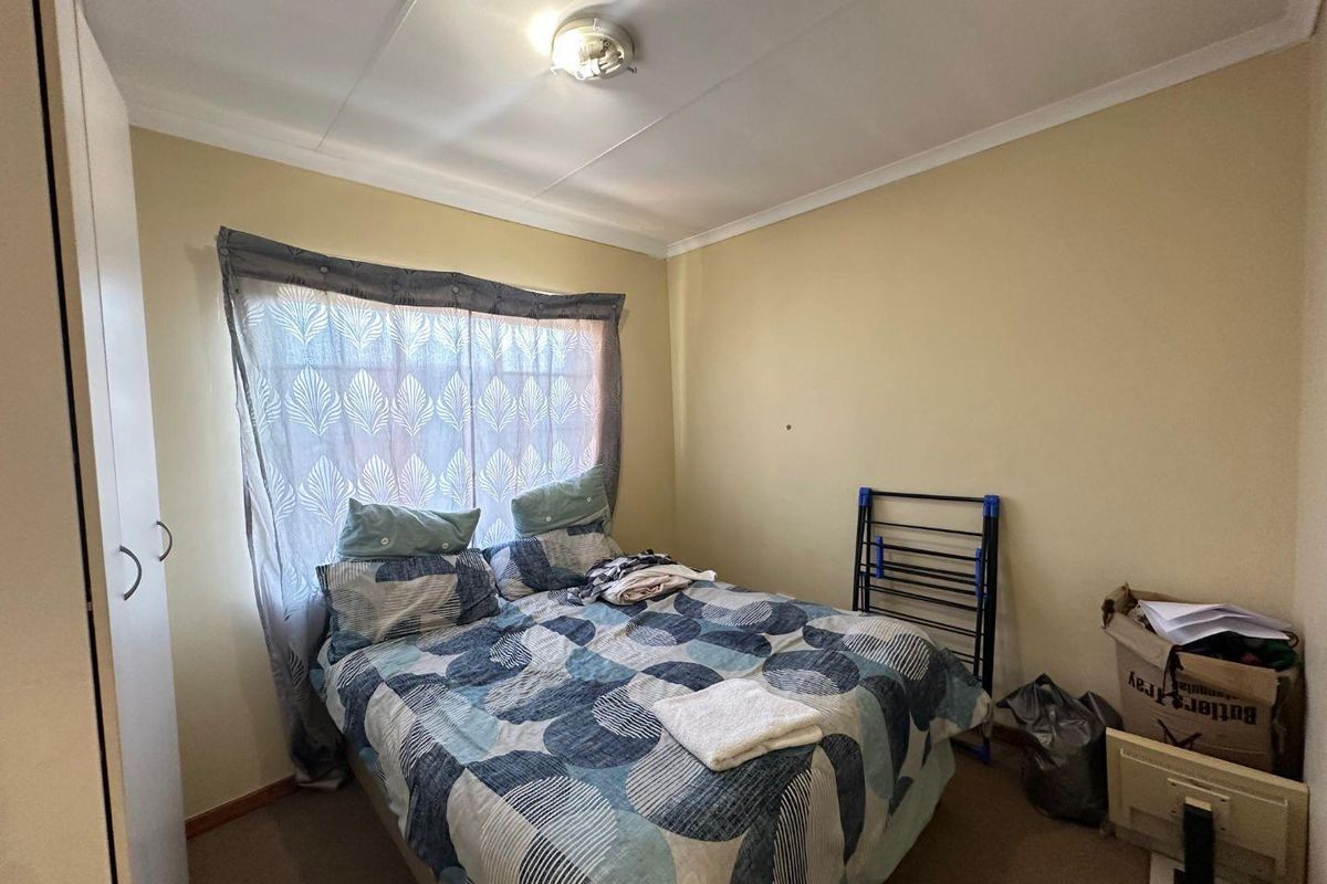 A standard bedroom featuring carpeted flooring, a built-in wardrobe, and a ceiling light fixture, providing a functional space for rest.