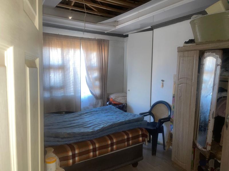 A bedroom featuring a built-in cupboard and window, currently requiring significant ceiling repairs and general maintenance to restore the space.