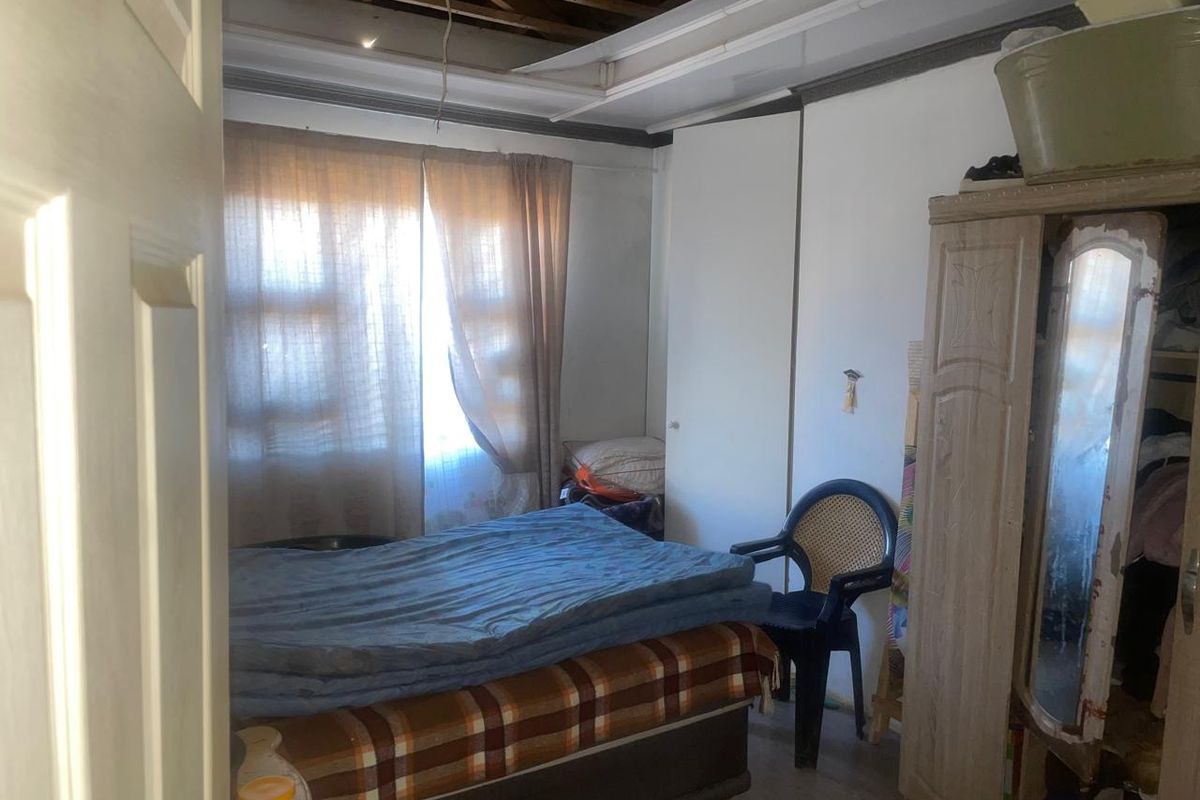 A bedroom featuring a built-in cupboard and window, currently requiring significant ceiling repairs and general maintenance to restore the space.