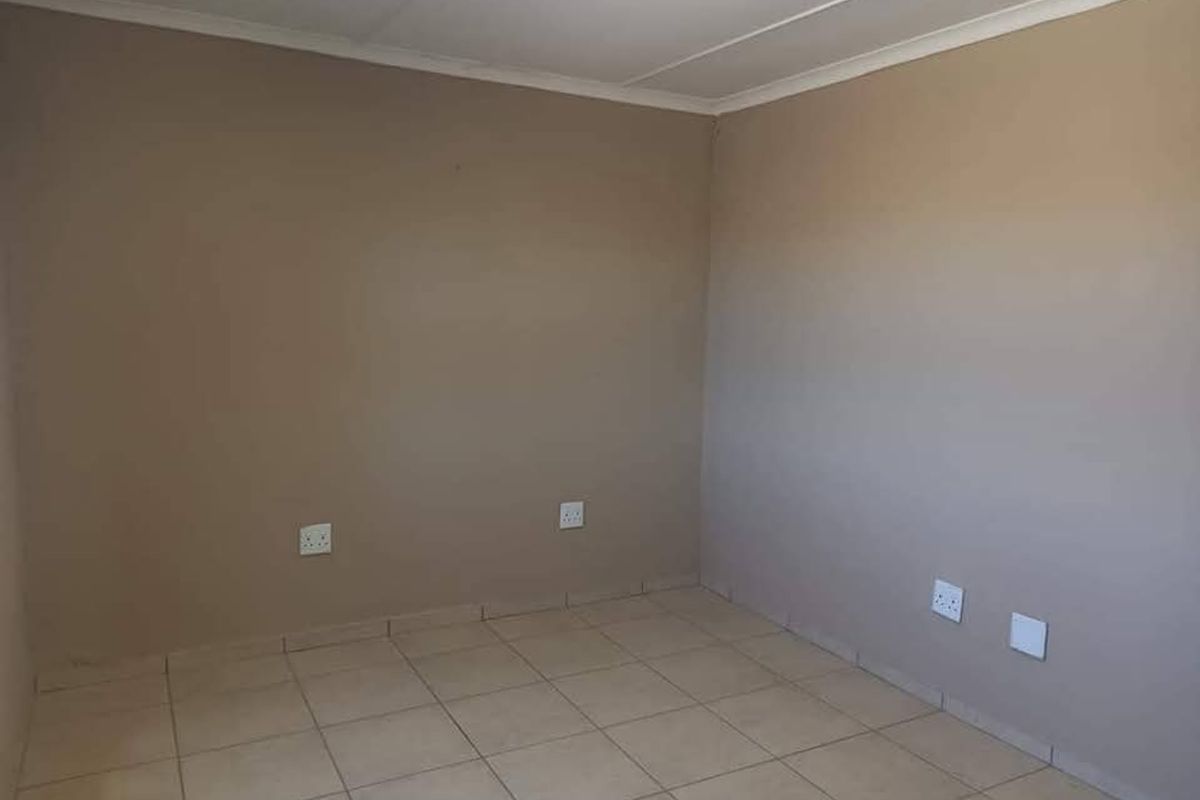A clean, empty room featuring neutral wall paint, tiled flooring, and standard electrical power points.