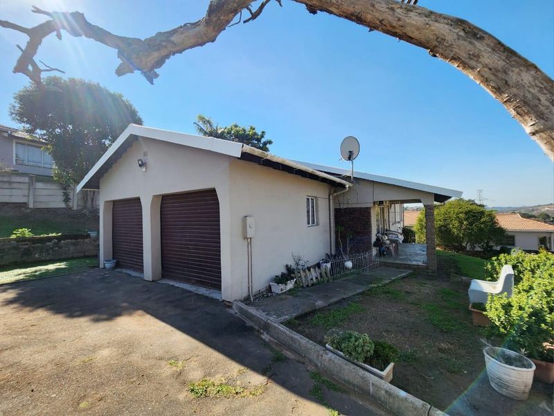 Exterior view of a house featuring a double garage with roll-up doors, a concrete driveway, and a covered patio area.
