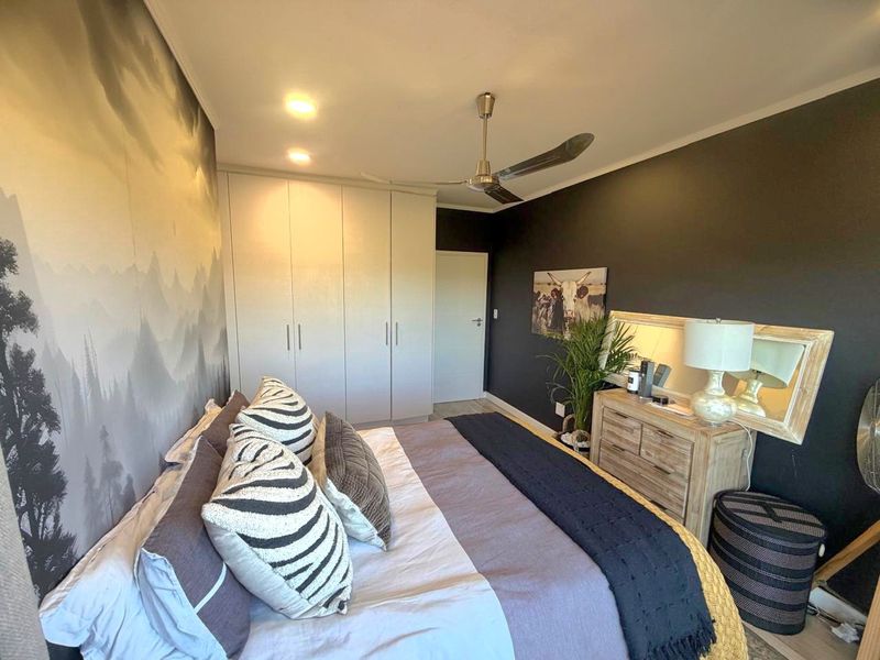 A well-maintained bedroom featuring built-in cupboards, a ceiling fan, and modern recessed lighting, creating a comfortable and functional living space.