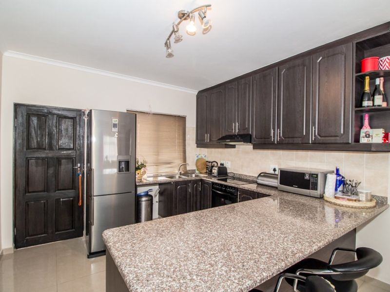 A functional kitchen featuring dark wood cabinetry, granite countertops, and a breakfast bar, providing ample storage and workspace.
