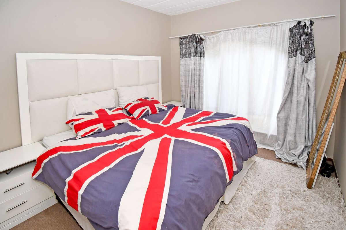 A bedroom featuring a built-in headboard and integrated bedside cabinetry, finished with neutral wall tones and carpeted flooring.